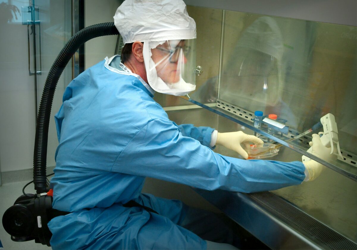 A doctor on a blue safe suit analysing samples